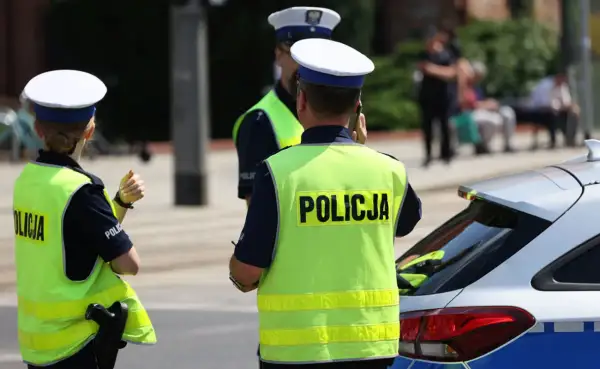 Policjanci w kamizelkach odblaskowych stoją obok radiowozu. Czy policja może wejść na teren prywatny bez nakazu?