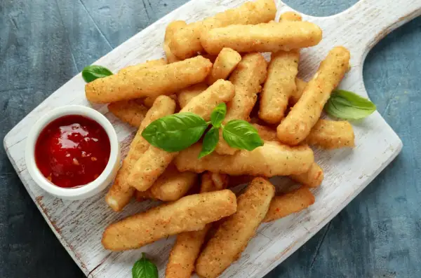 Jak zrobić frytki z halloumi – idealna przekąska na imprezę. Złociste paluszki serowe z sosem pomidorowym i bazylią.