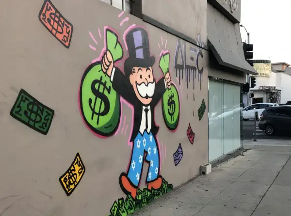 A vibrant graffiti drawing of the Monopoly Man, clutching bags of money, stands proudly on a wall. Dollar bills rain down around him, a testament to his wealth.