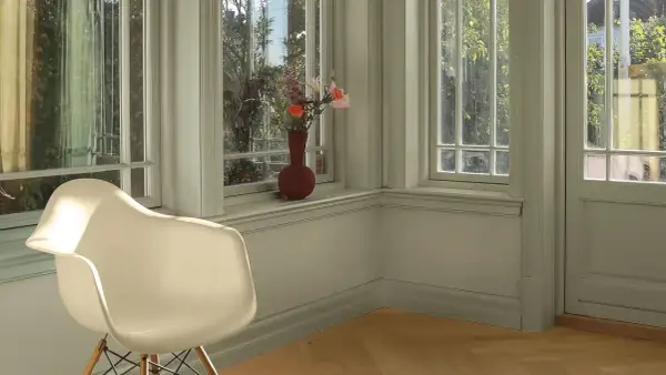 En ljus hall med en vit stol och en vas med blommor på fönsterbrädan. Väggarna är målade i en lugn grön nyans, vilket ger en harmonisk känsla.