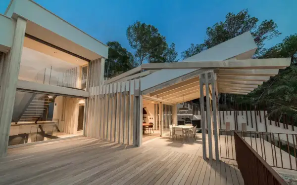 Terraza moderna con suelo de madera Accoya, pérgola y fachada acristalada.