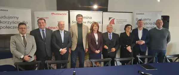Grupa osób pozuje do zdjęcia na tle banerów informujących o budowie obwodnicy Sokołowa Podlaskiego.