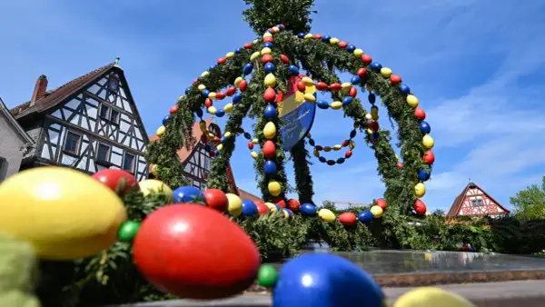 Bunte Ostereier schmücken einen Tannenkranz vor Fachwerkhäusern. Es gibt Karsamstag, die Vorfreude auf Ostern ist spürbar.