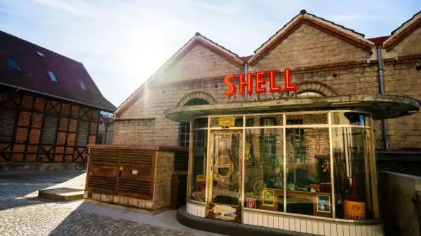 Retro Shell-Tankstelle im Motorworld Metzingen, mit Fachwerkhaus im Hintergrund.