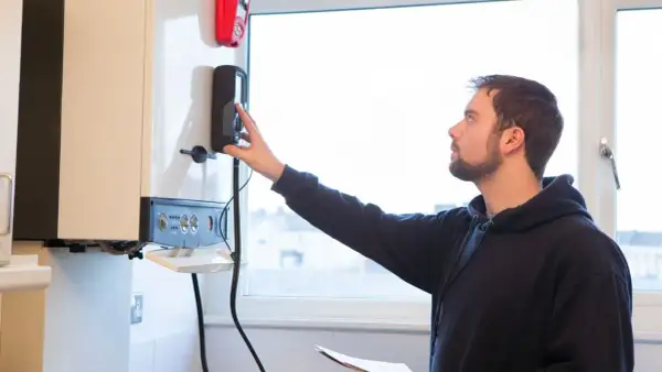 Un technicien ajuste la commande d'une chaudière à condensation.
