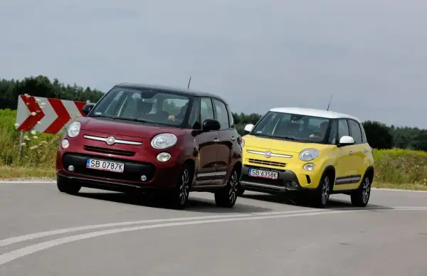 Dwa samochody Fiat 500L, jeden czerwony, drugi żółty, jadą po zakręcie drogi.
