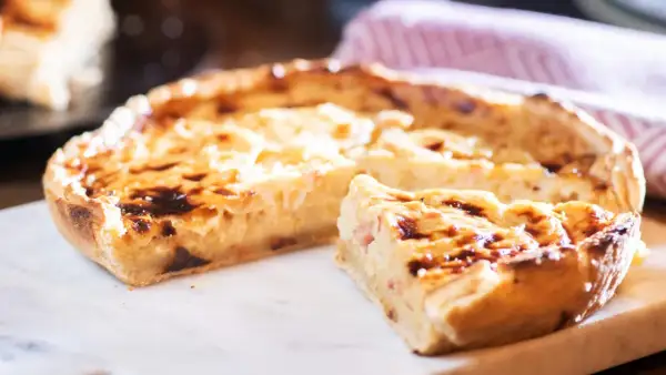 Ein köstliches Quiche Rezept, goldbraun gebacken, mit einem Stück zum Probieren.