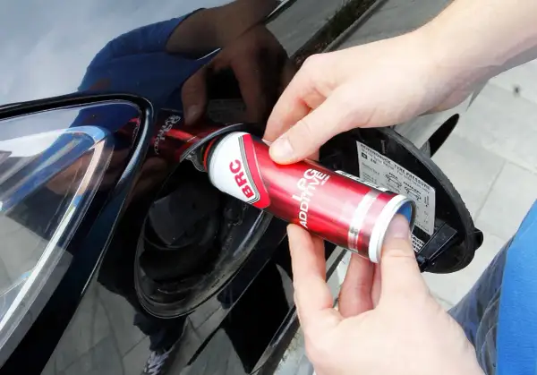 Ręce wlewają dodatek do LPG z puszki BRC do baku samochodu, dbając o czyszczenie wtrysków lpg.