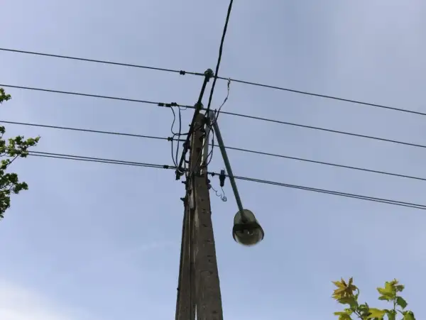 Słup energetyczny z wiszącą lampą uliczną, gdzie mogło dojść do kradzieży prądu. Policja bada sprawę.
