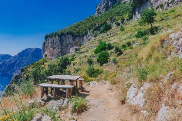 Un tavolo da picnic in legno attende i viaggiatori sul Sentiero degli Dei, con vista mozzafiato sul mare e sulle montagne.