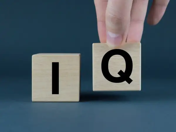 Dłoń układa kostkę z literą "Q" obok kostki z literą "I". Co to jest IQ?