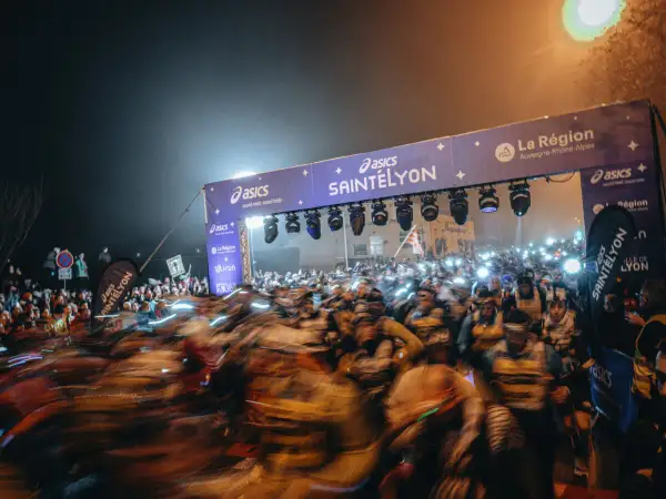 Foule de coureurs au départ de la SaintéLyon, sous un portique illuminé. Les résultats de cette course nocturne promettent d'être intenses.
