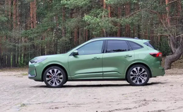 Zielony Ford Kuga Hybrid na tle sosnowego lasu. Elegancki SUV gotowy na przygodę.