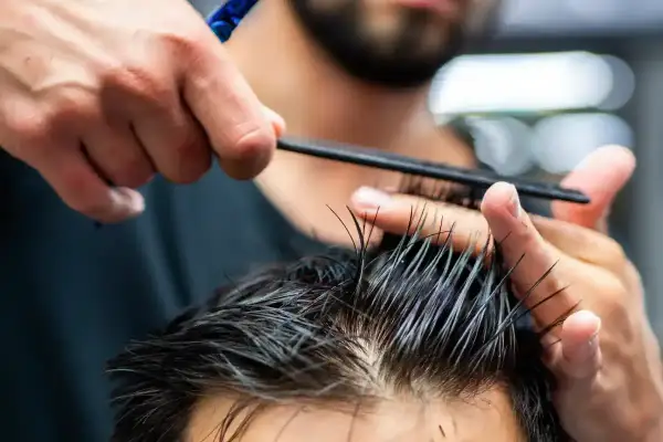 Strzyżenie męskie klasyczne maszynką krok po kroku. Fryzjer precyzyjnie modeluje włosy klienta grzebieniem i nożyczkami.