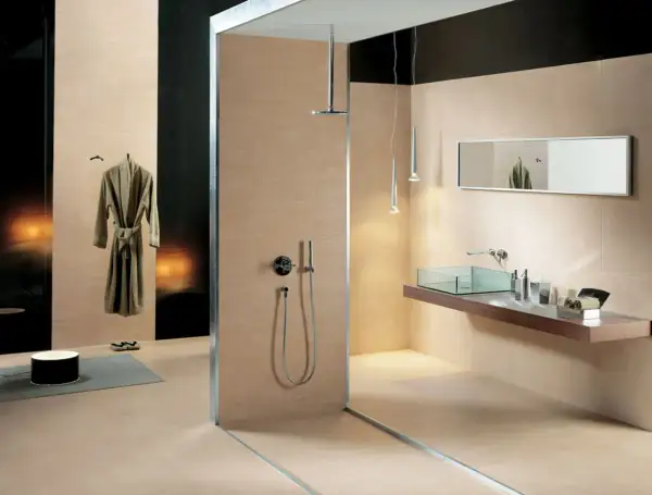 Salle de bain moderne avec douche vitrée, lavabo en verre, miroir et peignoir suspendu. Les carrelages respectent la norme PEI pour une durabilité accrue.