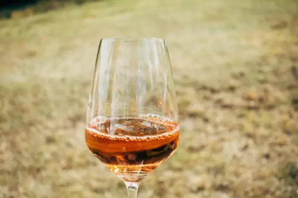 Un bicchiere di passito di Pantelleria, con il suo colore ambrato e le bollicine che danzano, pronto per essere gustato all'aperto.