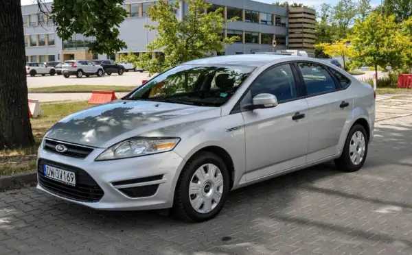 Srebrny Ford Mondeo MK4 2.0 TDCI zaparkowany na kostce brukowej przed budynkiem.