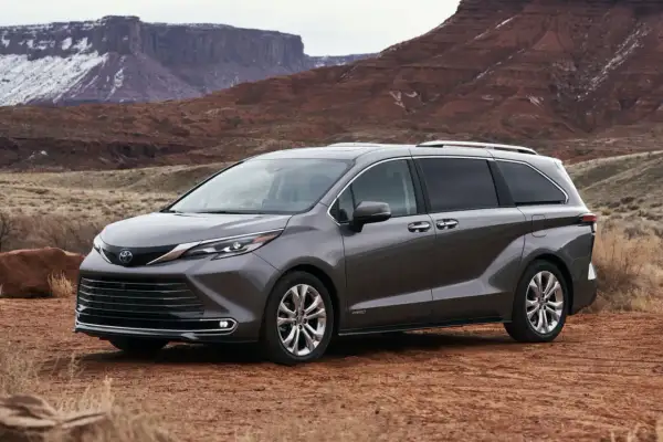 Szara Toyota Sienna na tle pustynnego krajobrazu z czerwonymi skałami.