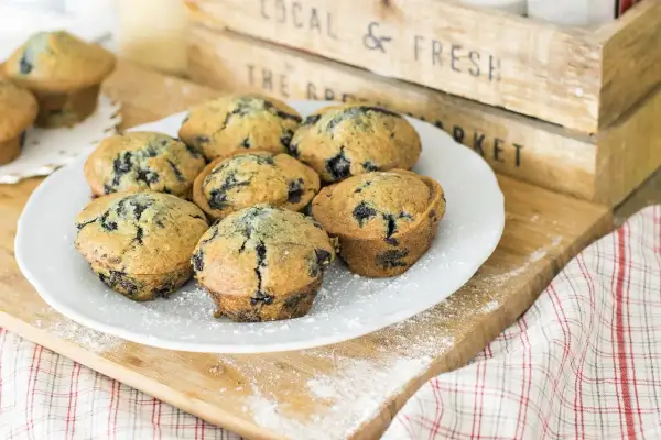 Plate of delicious muffin myrtille, sprinkled with powdered sugar, on a wooden board.