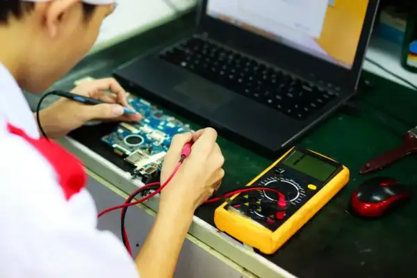 Technik elektronik bada płytę główną laptopa multimetrem. Zastanawiasz się, ile zarabia technik elektronik?