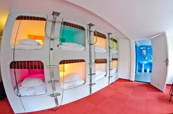 Wnętrze hotelu kapsułowego w Japonii z rzędami łóżek w kolorowych kapsułach.