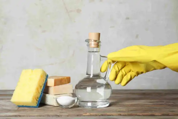 Ingredienti per un detersivo lavatrice fatto in casa da Benedetta: aceto bianco in una caraffa, sapone, bicarbonato e una spugna.