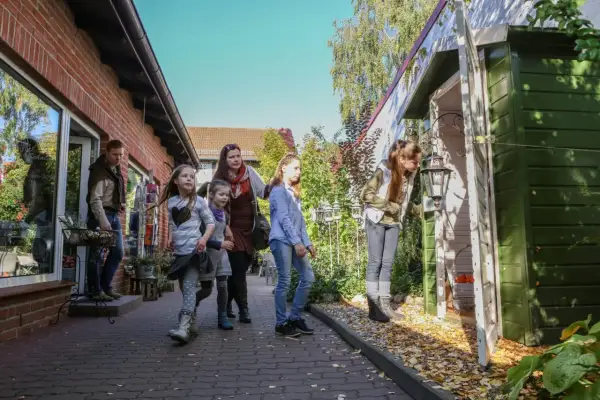 Familie erkundet die Templin Altstadt, vorbei an einem roten Backsteinhaus und einem grünen Schuppen mit Laterne.