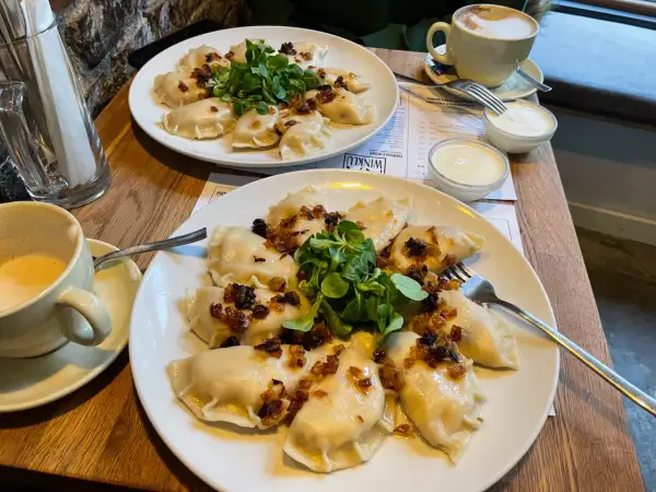 Pyszne pierogi z cebulką i zielenią – idealne pytanie: co zjeść w Poznaniu? Do tego kawa i śmietana.