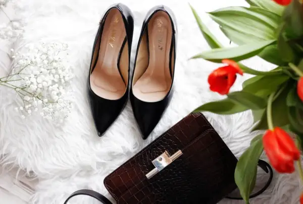 Eleganckie czarne szpilki, brązowa kopertówka i bukiet czerwonych tulipanów – idealne buty na prezent.