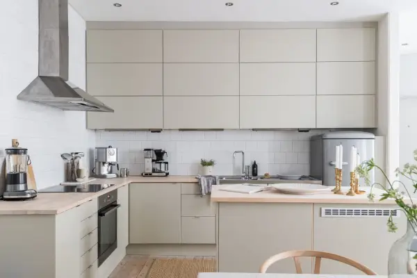 Beżowa kuchnia inspiracje: minimalistyczne szafki, drewniany blat, stalowy okap i eleganckie dodatki tworzą przytulną atmosferę.