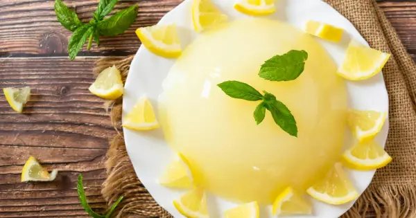 Delizioso gelo di limone su piatto bianco, decorato con spicchi di limone fresco e foglie di menta.