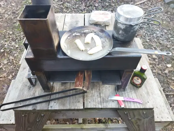 Poêle rocket fait maison, avec des bananes qui dorent dans une poêle, une marmite et une bouteille de rhum Negrita.