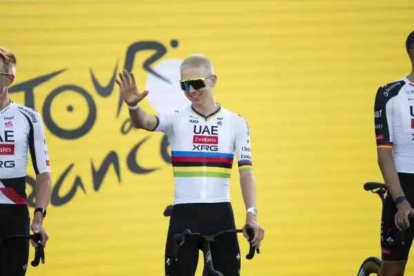 Radfahrer mit bunten Trikotfarben der Tour de France winkt fröhlich.