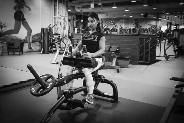 Kvinna tränar sittande vadpress på gym.