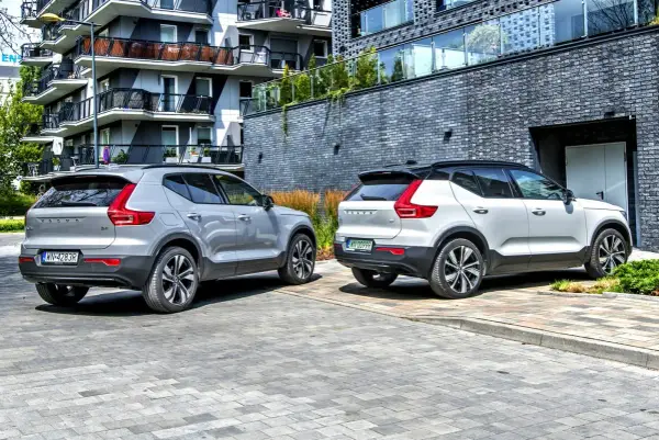 Dwa modele Volvo XC40, jeden srebrny, drugi biały, zaparkowane przed nowoczesnym budynkiem.