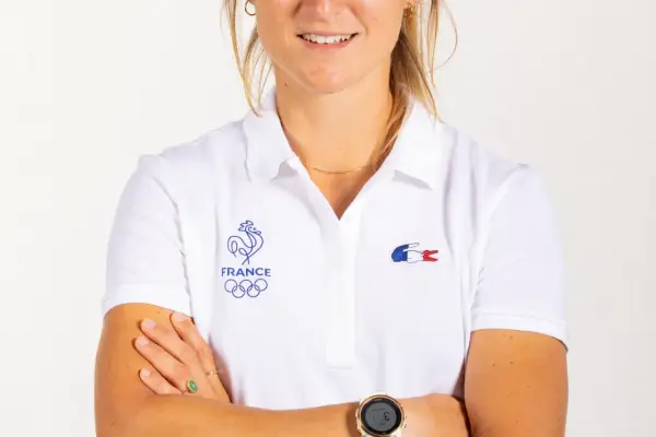 Manon Audinet, athlète française, porte un polo blanc avec les anneaux olympiques et le coq gaulois.