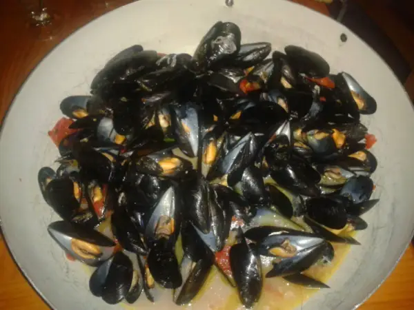 Un'abbondante impepata di cozze in un piatto largo, con pomodorini e un sughetto invitante.