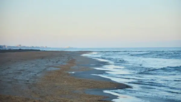 Plaża nad morzem Kaspijskim, które wysycha. W oddali widać zabudowania.