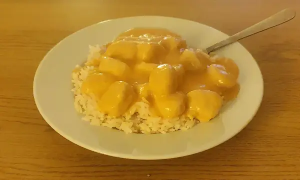 En tallrik med ris och krämiga fiskbullar i en gul sås. En nyttig och god måltid.