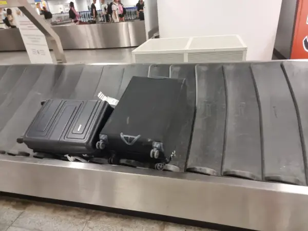 Dwa bagaże, w tym czarna walizka, czekają na odbiór na taśmie bagażowej. To typowy widok po przylocie liniami Ryanair.