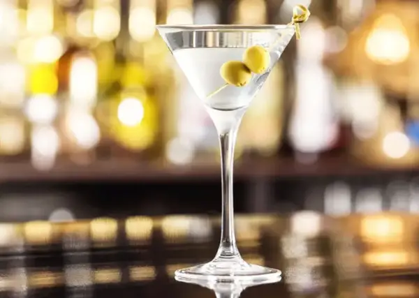 Klasyczny martini dry przepis: schłodzony gin, odrobina wermutu i dwie oliwki. Idealny drink na wieczór.