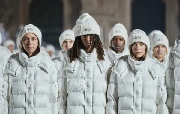 Grupa osób w białych kurtkach i czapkach Moncler. To właśnie moncler co to za firma – marka znana z luksusowej odzieży zimowej.