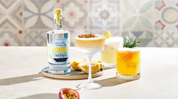 Erfrischender Vodka Sour mit Passionsfrucht und Zitrone, daneben ein weiterer Cocktail mit Ananas. Eine Flasche Zitronen-Wodka steht bereit.