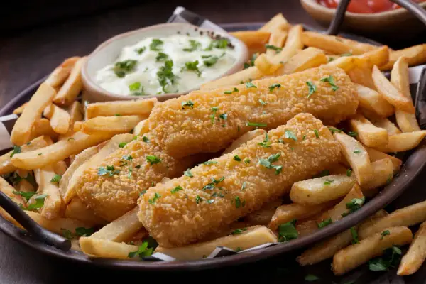 Knusprige Fischstäbchen und Pommes Frites, perfekt paniert ohne Ei, serviert mit einer cremigen Dip-Sauce und frischer Petersilie.