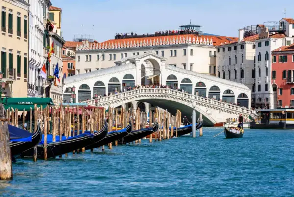 Gondoles amarrées près du célèbre Ponte di Rialto, avec des touristes admirant la vue sur le Grand Canal.