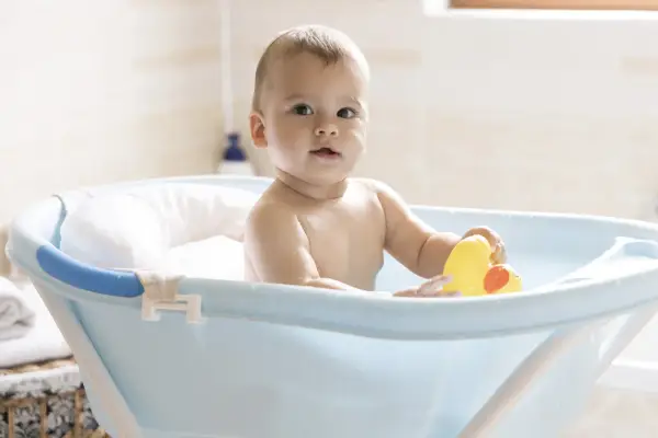 Urocze dziecko w niebieskiej wanience z żółtą kaczką. Kąpiel w wanience jest świetną zabawą, a dziecko może w niej przebywać, dopóki nie zacznie samodzielnie siadać i wstawać.