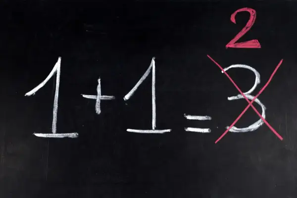 Na czarnej tablicy napisano kredą: 1+1=2. Liczba 3 jest przekreślona, jakby to był trudny egzamin dojrzałości.
