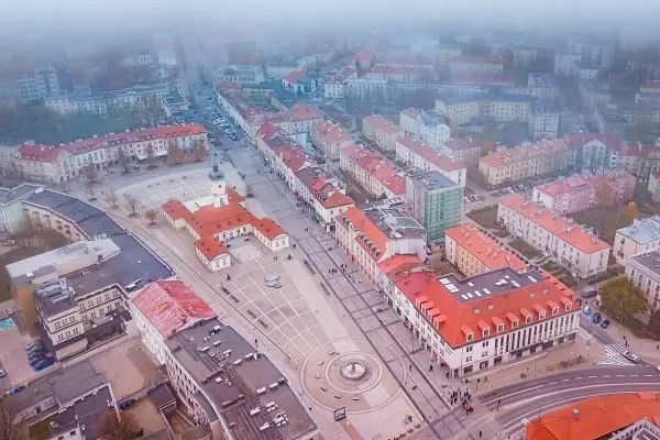 Widok z lotu ptaka na rynek Kościuszki w Białymstoku, otoczony kamienicami i budynkiem ratusza.