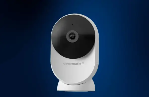 Weiße Homematic IP Überwachungskamera mit schwarzem Objektiv vor blauem Hintergrund.