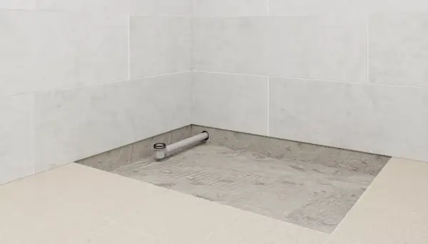 Installation d'un receveur de douche : un siphon est posé sur une chape avant le carrelage.